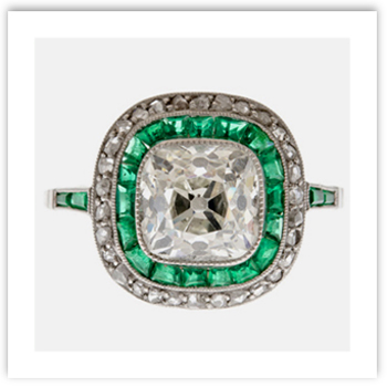 Cushion cut diamond surrounded by emeralds